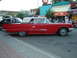 1990 Ford Thunderbird - A classic red convertible with a white top is parked on the street, with other vehicles and buildings in the background.