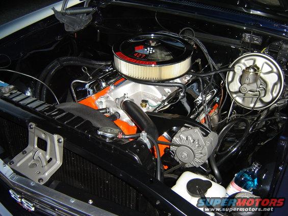 Engine bay with chrome air cleaner labeled 427, orange engine block, and black hoses