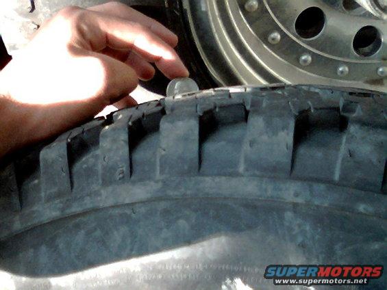 hand checking tire tread depth with a coin