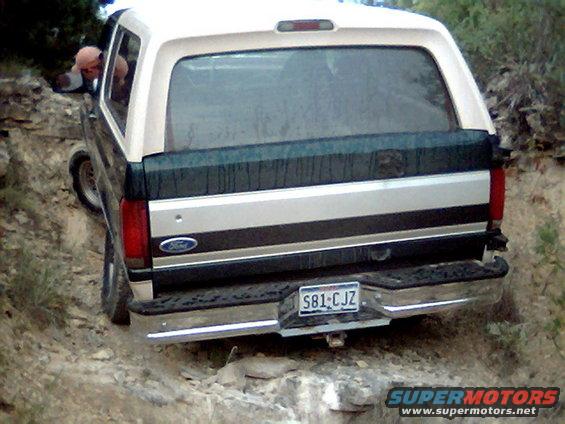 Two-tone 1992 Ford Bronco, white top and dark green/silver body, on a rocky incline