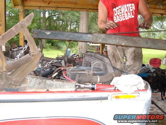 Engine bay with tools and a person working. Red and white vehicle