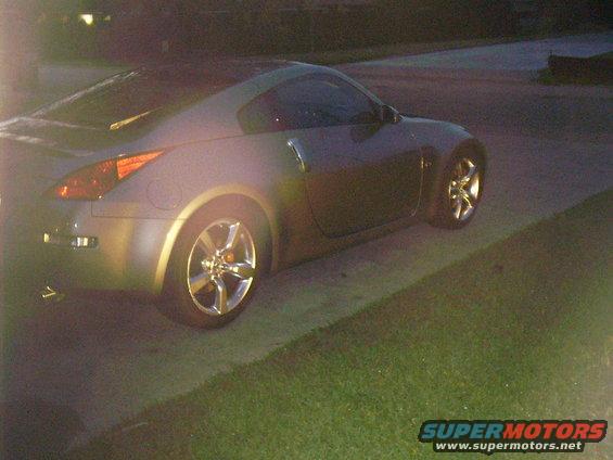 Car parked on driveway at dusk. Side view shows rear wheel and part of front wheel