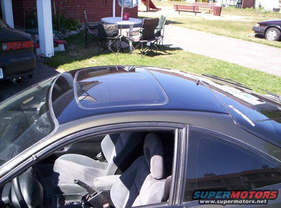 car interior with sunroof, gray seats, and center console. Another car is parked to the left