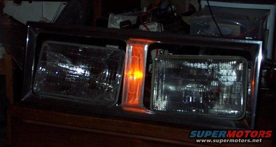 Chrome-trimmed headlight assembly with two rectangular headlights and an orange turn signal