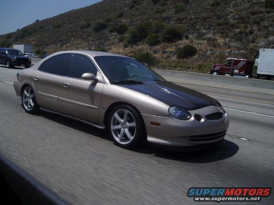 Tan sedan with black hood driving on highway