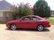 2002 Nissan SE-R - This red 2002 Nissan SE-R sedan is shown from the side, parked in front of a house with flowering trees.