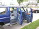 1995 Ford C-350 (Centurion Conversions) - The interior of a blue SUV is visible with all doors open, revealing cloth seats and wood accents on the door panels.