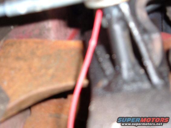 Close-up of rusty metal and black engine component with a red wire