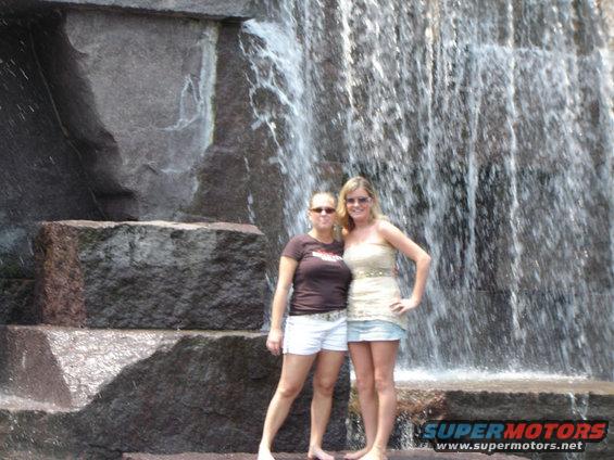 Two women pose in front of a cascading waterfall
