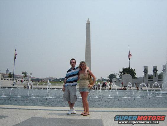 Couple poses at the World War II Memorial with Washington Monument in background