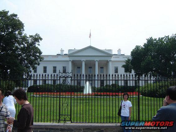 White House with a fountain and people in front of a fence