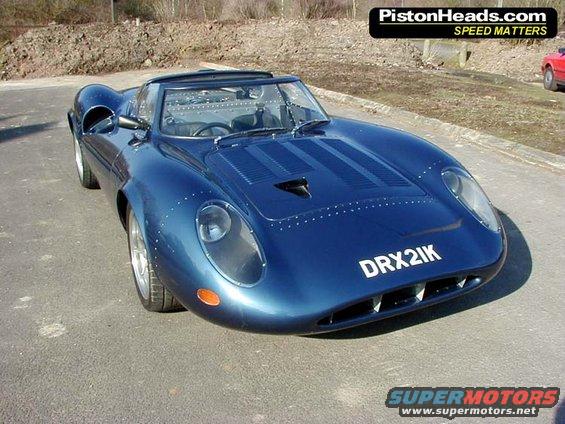 Blue sports car with rivets on the body and a license plate that reads DRX2IK