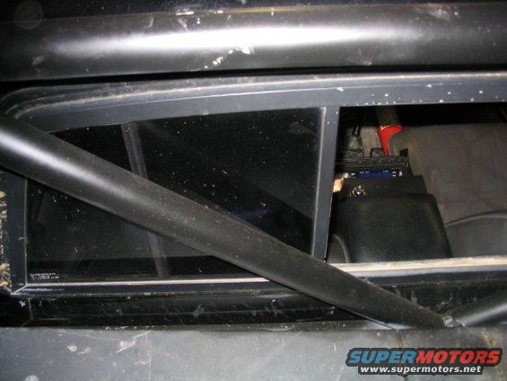 Roll cage inside a vehicle, looking through the rear window at some equipment