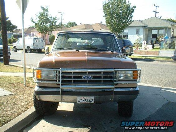 Brown Ford Bronco with chrome grille guard, parked on street