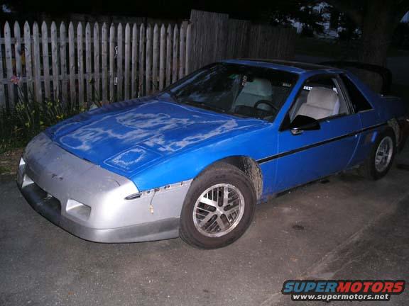 Blue 1984 Pontiac Fiero with a silver front bumper and faded paint on the hood
