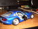 1988 Ford Bronco - A blue toy sports car sits on a wooden surface with its doors open, revealing the interior.