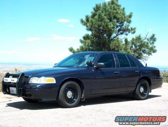 Dark blue 2001 Ford Crown Victoria police car with a push bar, parked outdoors