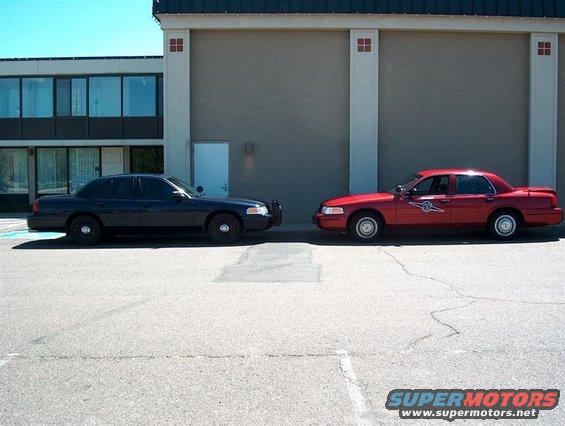 Side view of black and red 2001 Ford Crown Victoria police cars parked