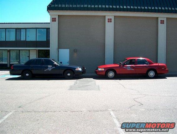 Black and red 2001 Ford Crown Victoria police cars parked side-by-side