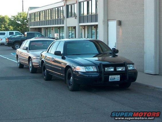 Black 2001 Ford Crown Victoria police car with push bumper and ADAM-12 license plate