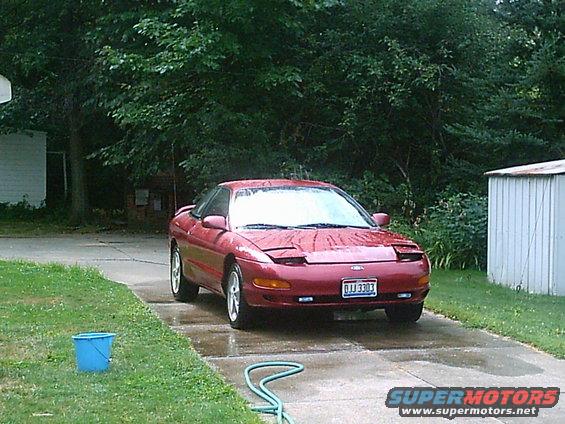Red 1993 Ford Probe coupe parked on a wet driveway, front view