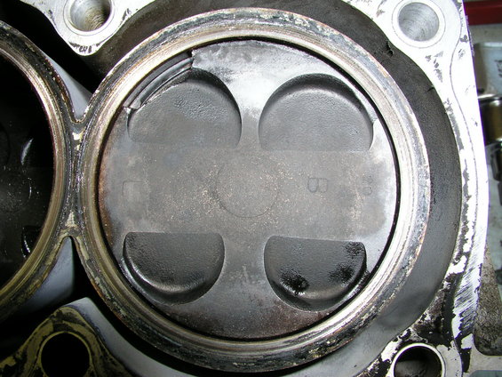 Close-up of a damaged engine piston inside a cylinder bore