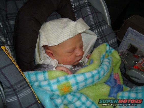 Newborn baby sleeping in a car seat, wrapped in a blanket