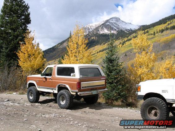 Brown Ford Bronco parked on a dirt road with a mountain in the background