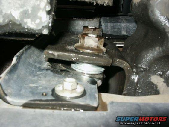 Close-up of a bolted bracket and washer on a vehicle's suspension