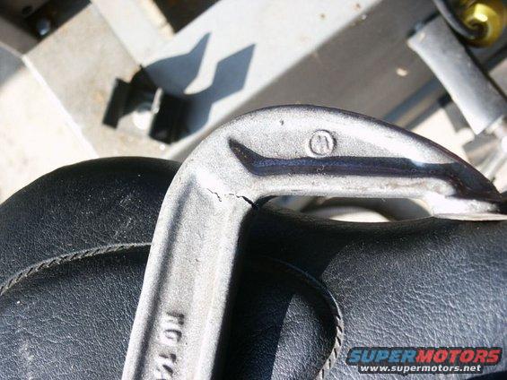 Cracked metal part with 'KG 74' visible, resting on a black seat