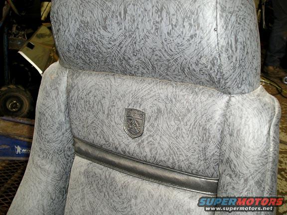 Close-up of a car seat with a shield emblem and patterned upholstery