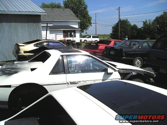 White Pontiac Fiero with black trim and a damaged front fender, parked outdoors