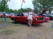 1978 Ford Mustang II - A woman poses next to a red 1978 Ford Mustang II convertible with its hood up at an outdoor car show.