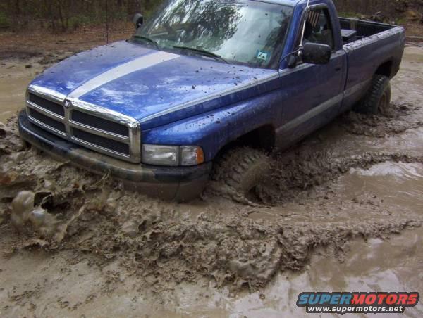 Blue 1995 Dodge 1500 stuck in deep mud, front wheel submerged