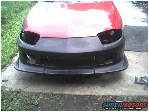 red car front end, missing headlights, with a black aftermarket bumper installed