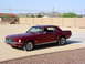 1967 Ford Mustang - A classic red 1967 Ford Mustang coupe is shown from a three-quarter front view in an outdoor setting.