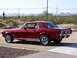 1967 Ford Mustang - A red 1967 Ford Mustang coupe is viewed from the rear three-quarter angle in a desert setting.