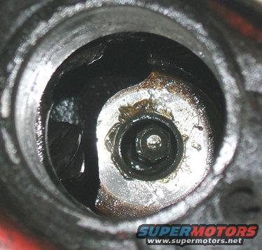 Close-up of an engine part with visible bolt and SuperMotors.net logo