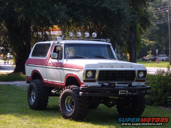 Lifted 1978 Ford Bronco with red and white paint, off-road tires, and a light bar on the roof