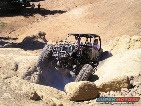 Custom off-road buggy with a roll cage navigating a rocky terrain