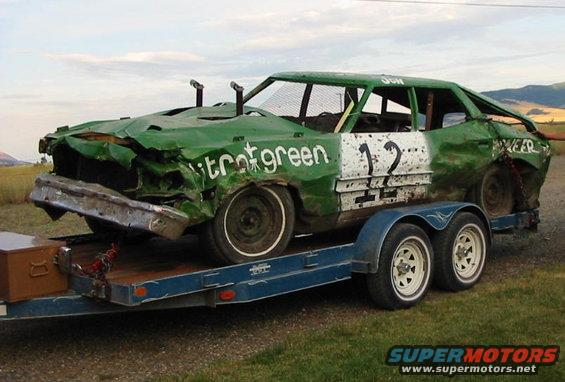 Green 1973 Ford Wagon demolition derby car on a trailer, heavily damaged front end, number 12 on door