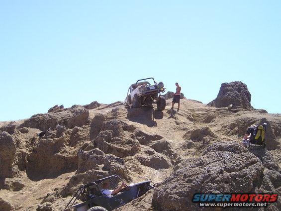 Off-road vehicles climbing rocks under a clear blue sky