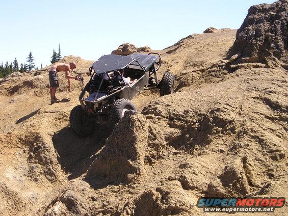Black off-road buggy climbing a steep, rocky incline