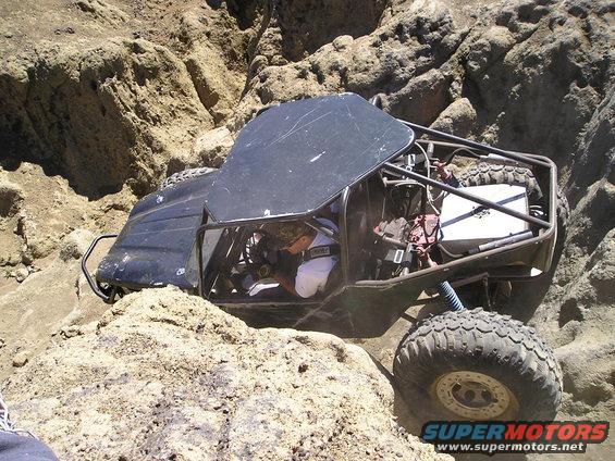 Black off-road buggy with roll cage stuck between rocks