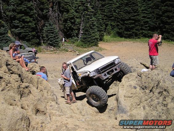 White off-road SUV climbing rocks with large tires