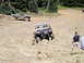 1989 Ford Bronco - Two trucks tackle a challenging off-road course with steep inclines and rocky terrain.