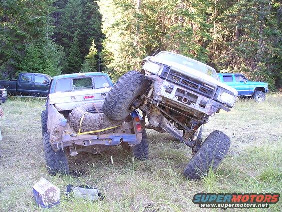 Two off-road trucks stuck in the mud, one on top of the other