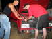 1991 Volkswagen Golf - Two men are gathered around the open engine bay of a red car, appearing to work on its components.