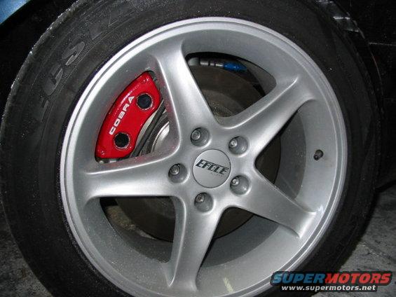 Close-up of a silver 5-spoke wheel with a red brake caliper labeled 'COBRA'