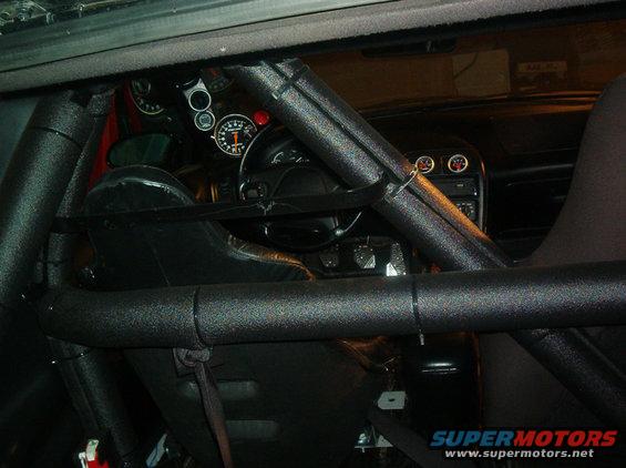 Interior view of a 1995 Ford Probe with a roll cage, racing seats, and aftermarket gauges